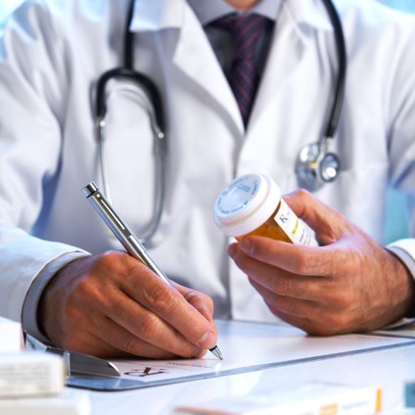 A doctor diligently writes notes on paper with a pen, showcasing a commitment to patient care and attention to detail.